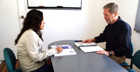Foto de un instructor y una alumna sentados en una aula aprendiendo ingl&eacute;s